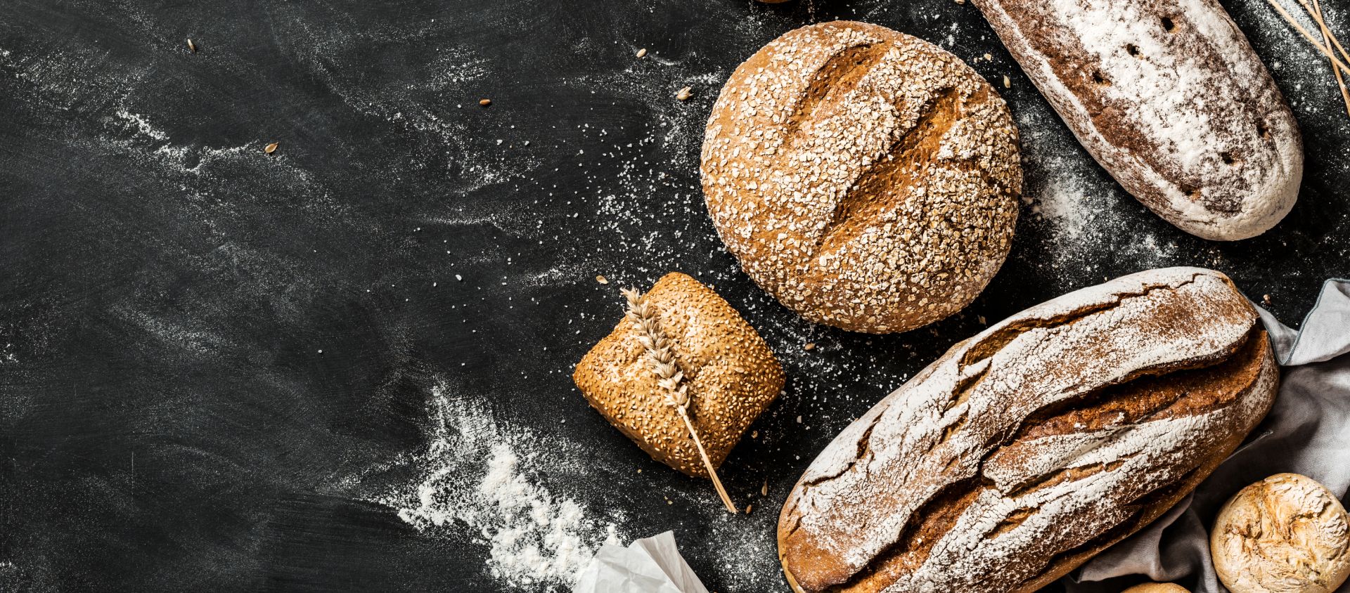 Verschiedene Brotsorten auf bemehlter Fläche mit Weizenähre