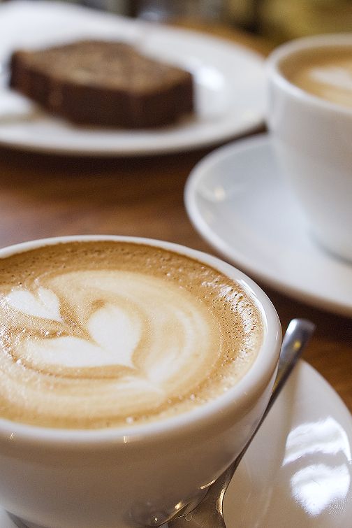 Tasse Kaffee mit Latte Art auf Untertasse und Löffel