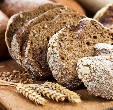 Geschnittenes Brot mit Weizenähren im Vordergrund